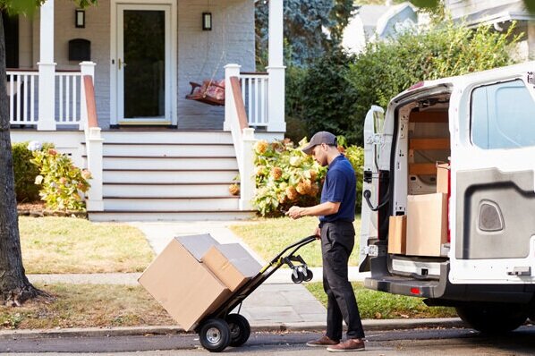 Courier with packages on hand truck making a residential home delivery